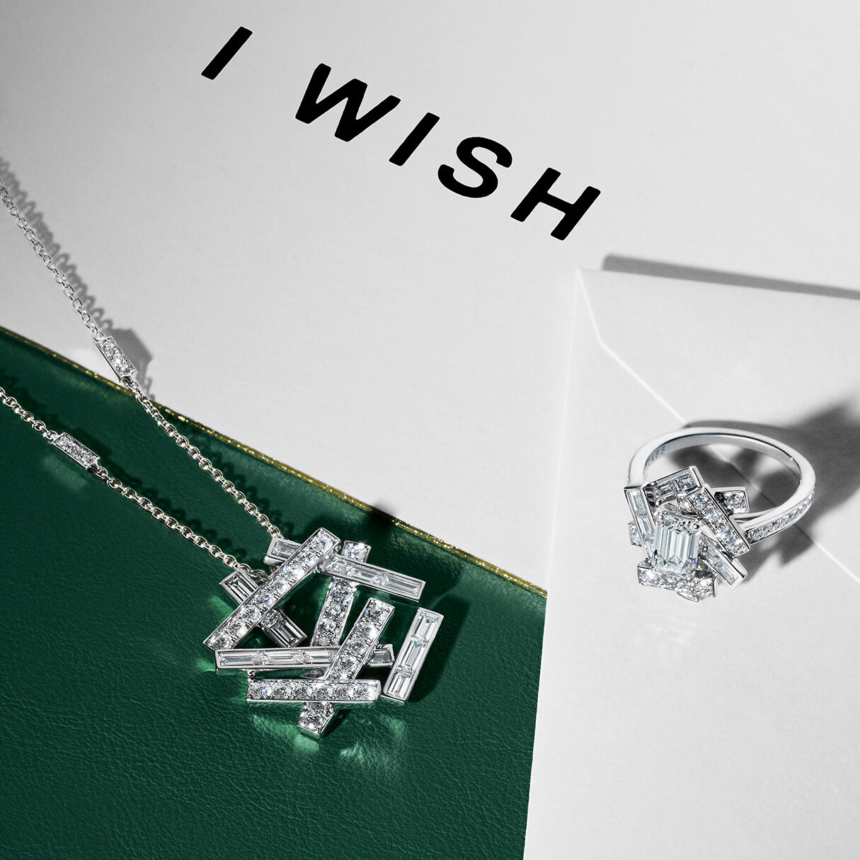 Still life image of Graff diamond collection Threads necklace and ring positioned on and 'I WISH' festive greetings card 