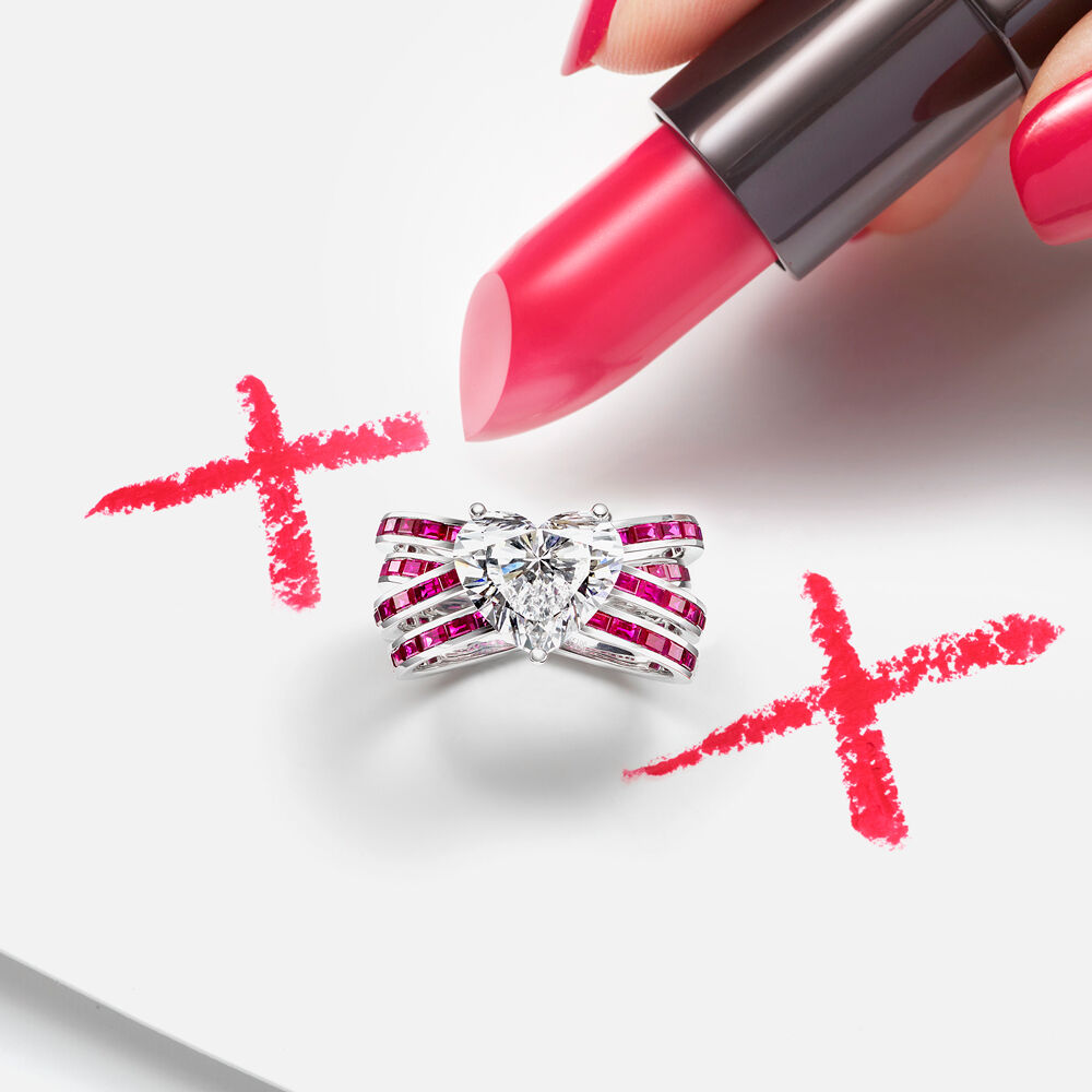 A Graff Ruby and diamond ring featuring a 4.01 carat D colour heart shape diamond with a lady’s hand holding a lipstick