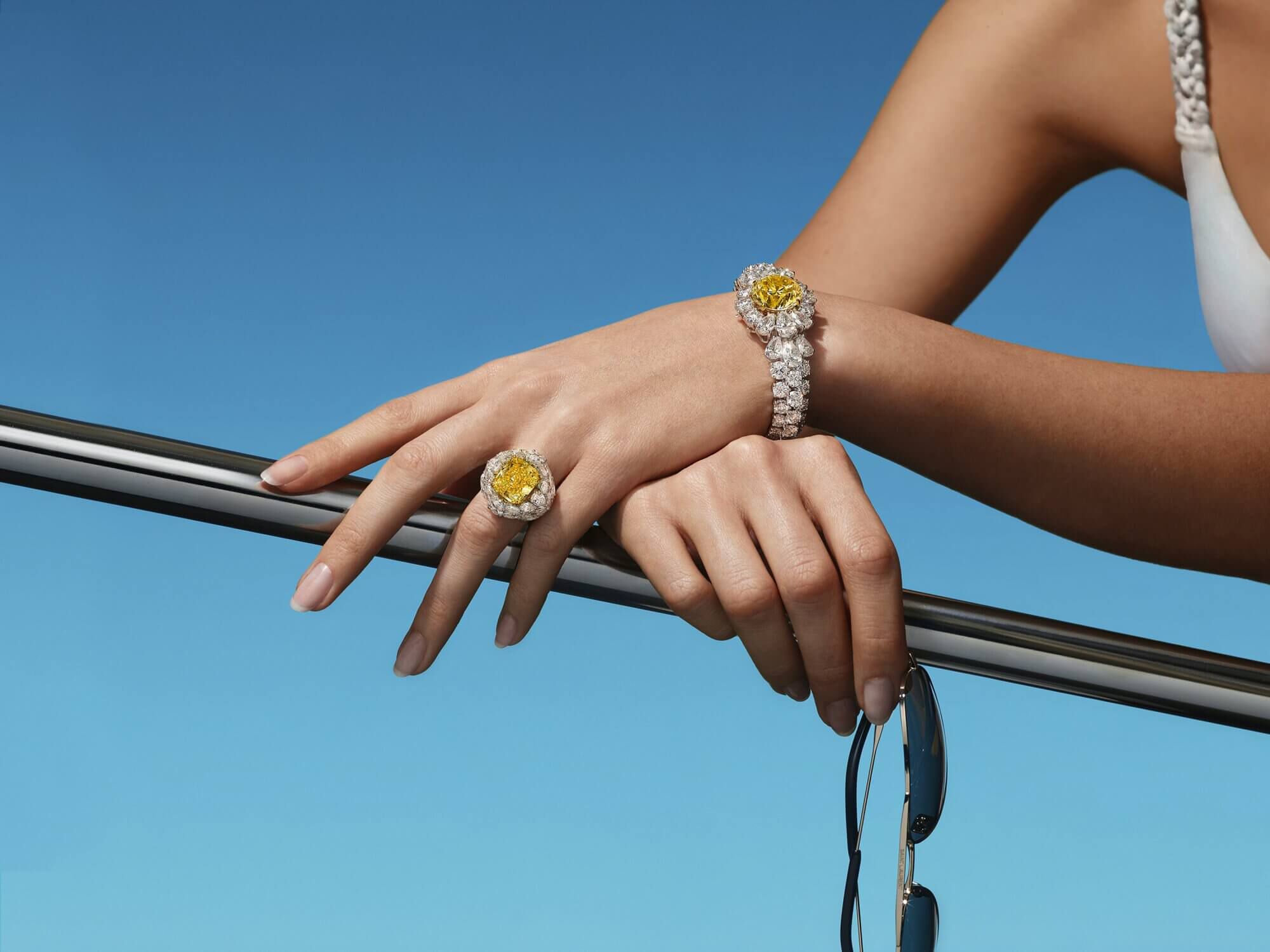 A lady on a boat wearing a yellow and white diamond Bracelet and ring from the Graff high jewellery collection