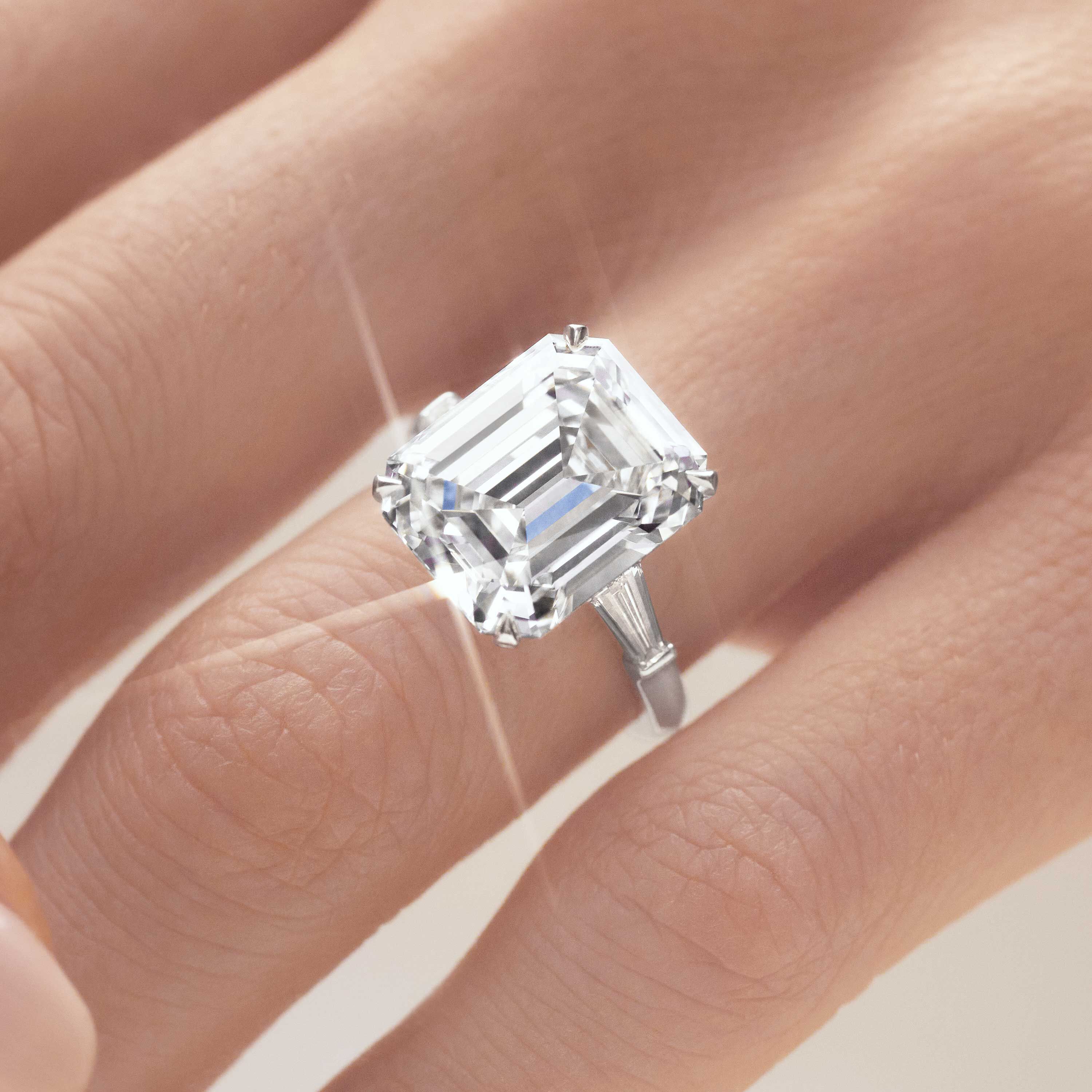 Close up of a Graff emerald cut diamond engagement ring wore by a model