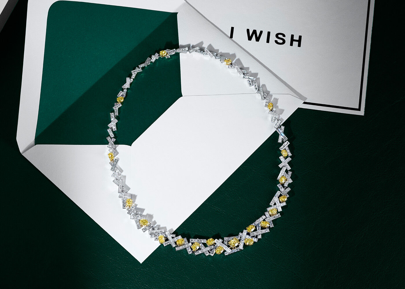 Yellow Diamond Jewellery, still life of Graff Threads Yellow and White Diamond High Jewellery necklace a top an 'I WISH' festive greetings card