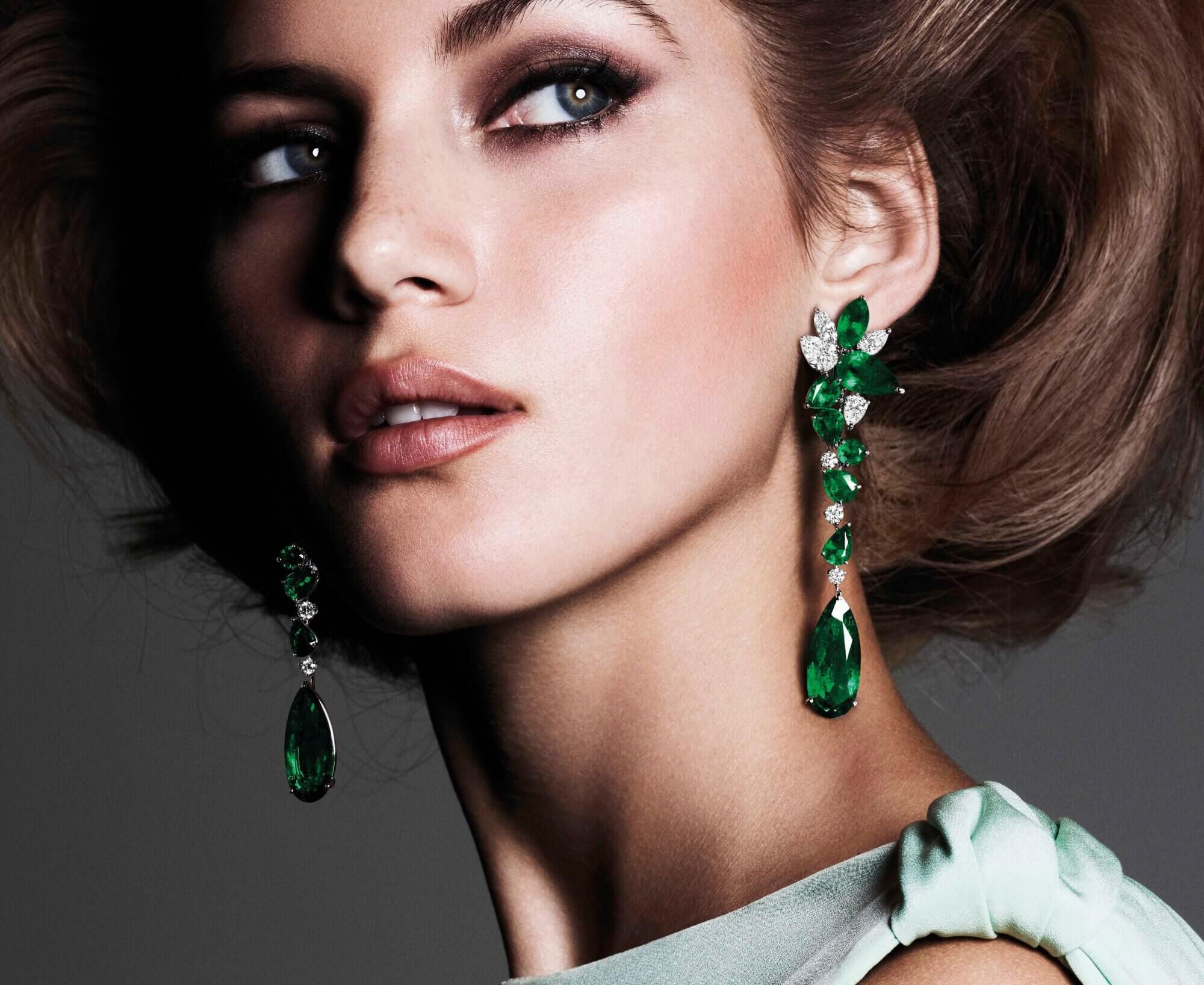 close up of a model wearing Graff emerald and diamond earrings