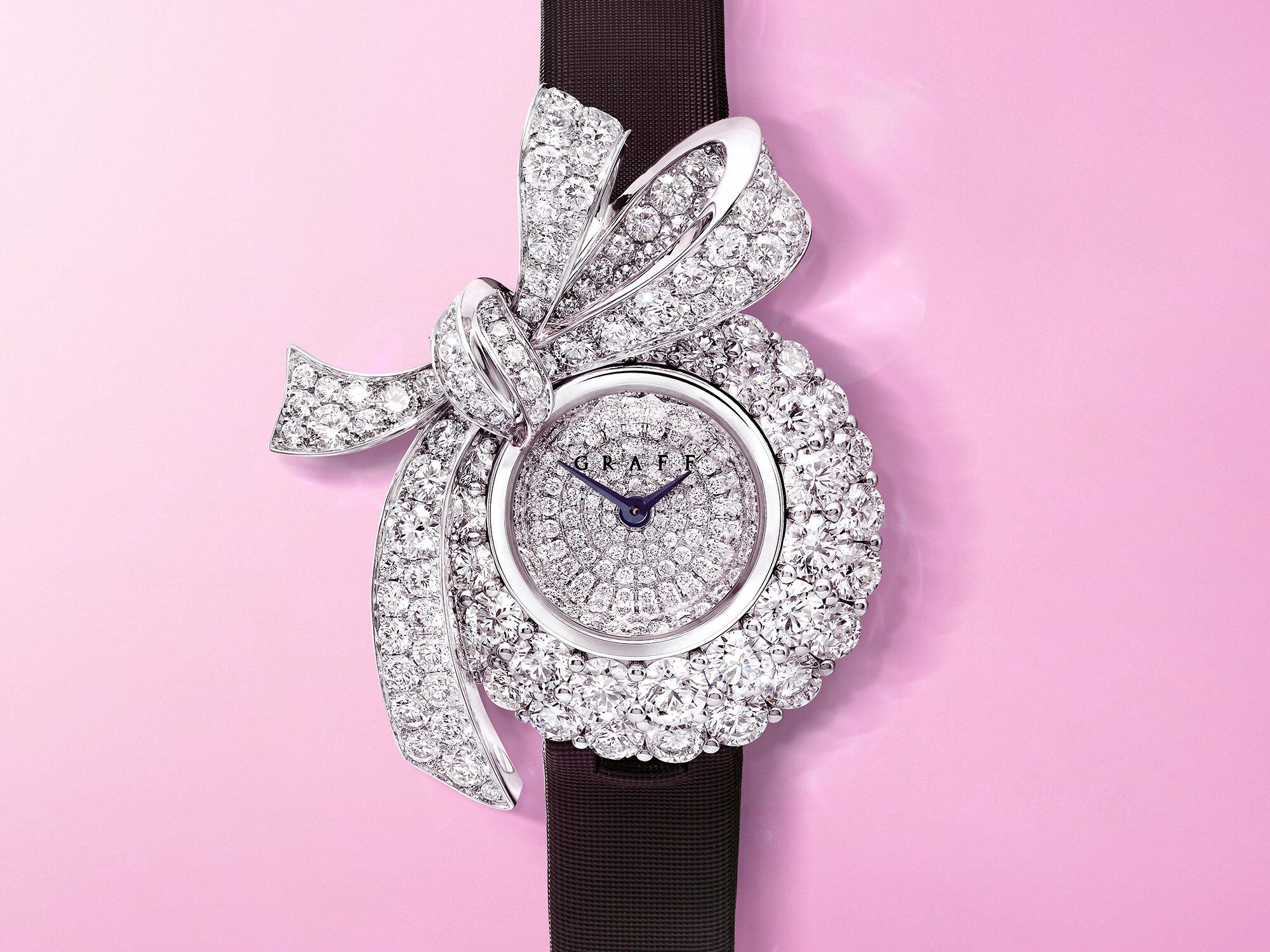 A Graff Tilda's Bow diamond watch with pear shape drop on a pink background