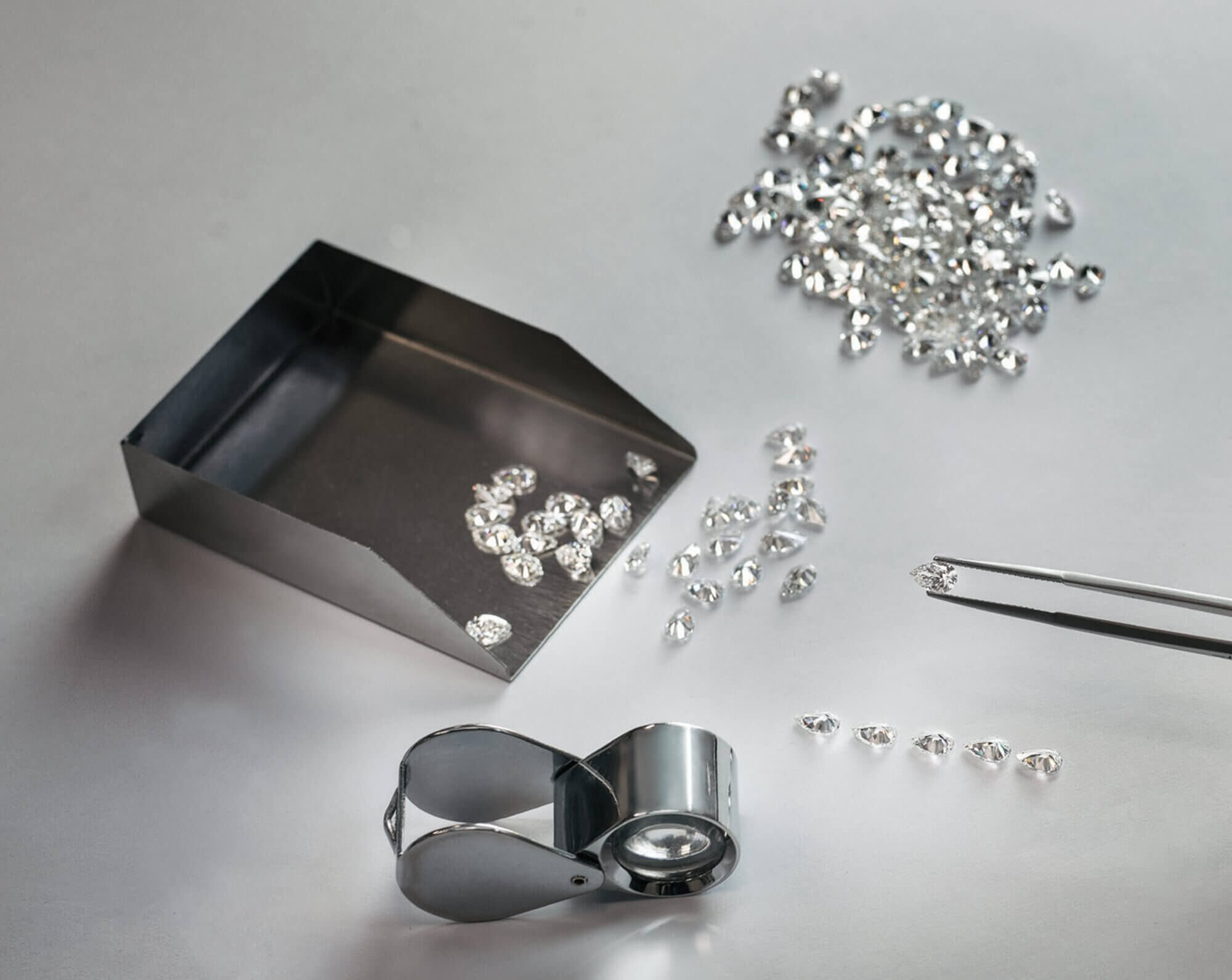 A collection of loose diamonds with a jewellers loupe