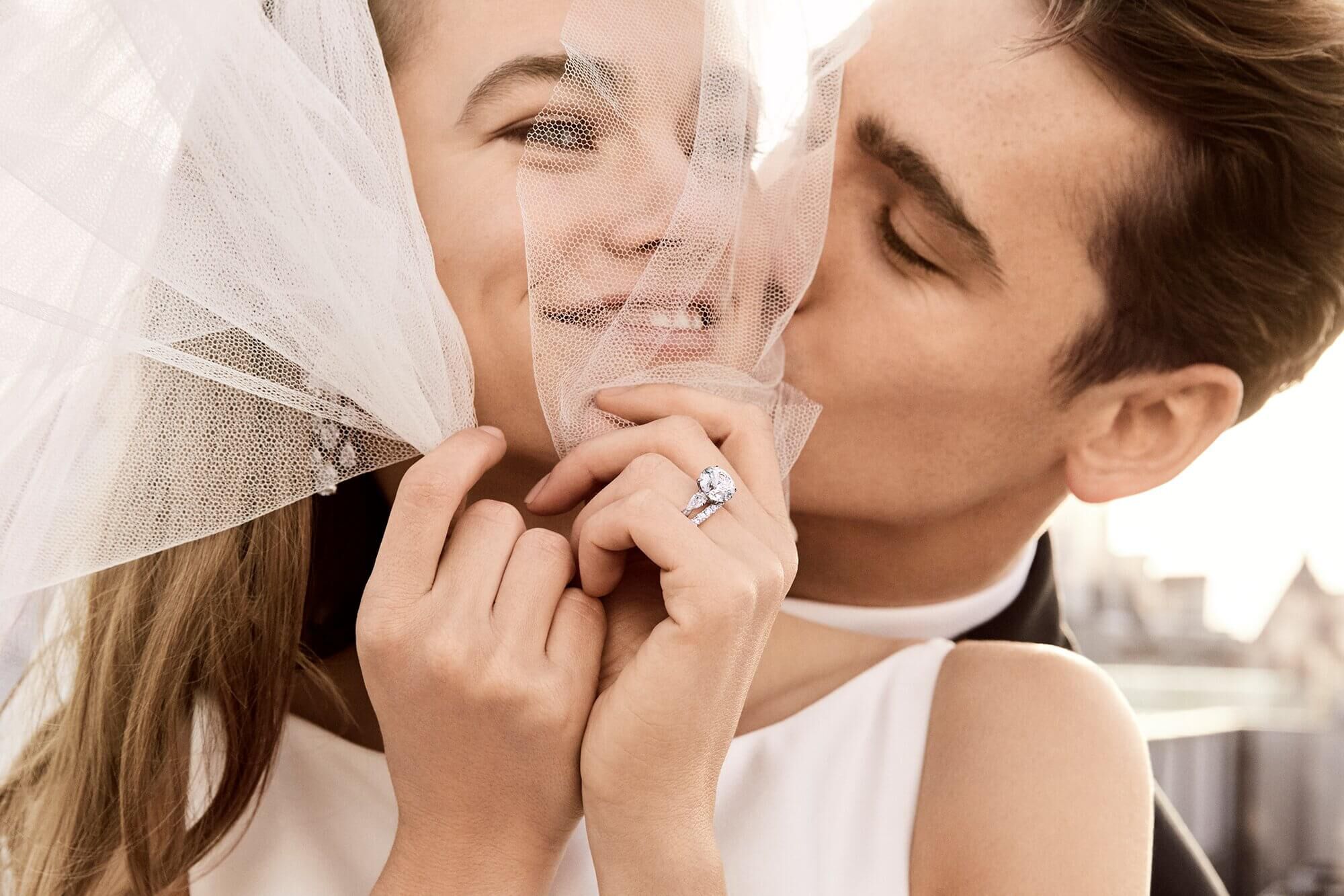 A man is kissing a lady wearing a Graff diamond engagement ring
