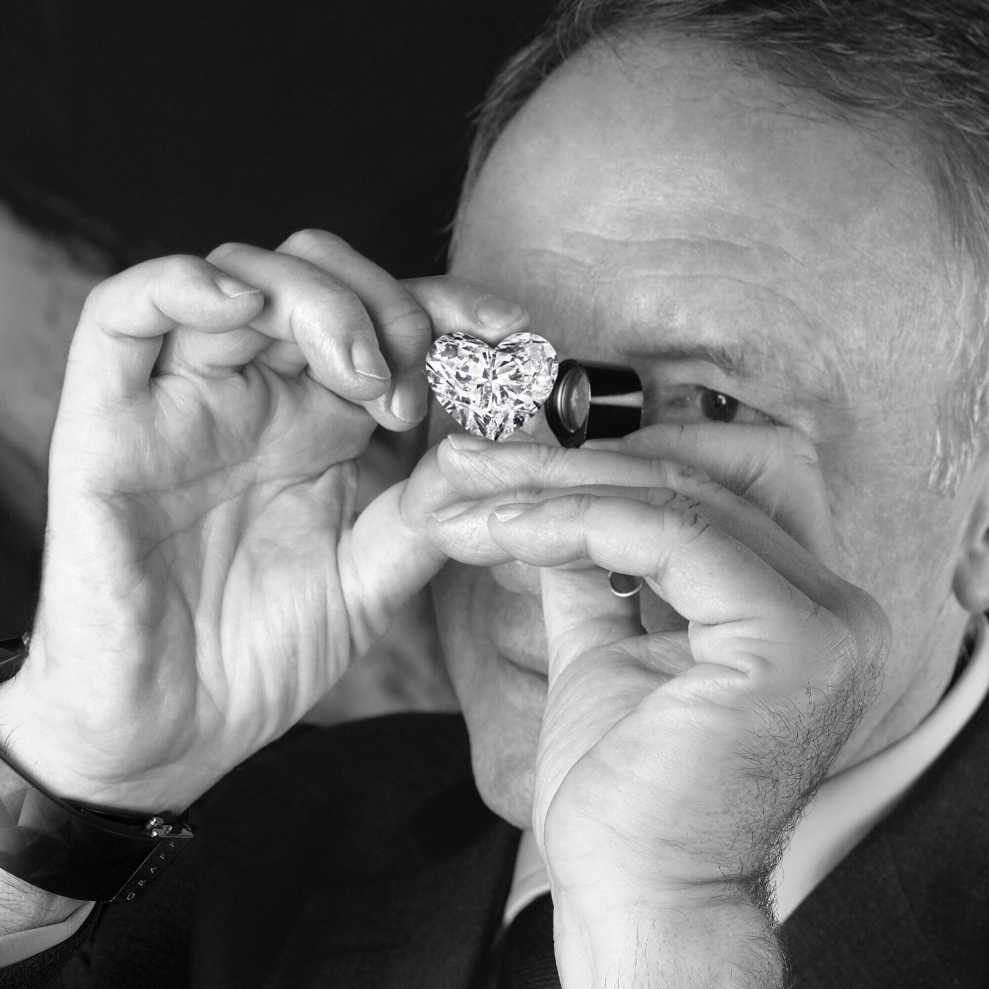 Mr Laurence Graff looking into a heart shape diamond through a loupe
