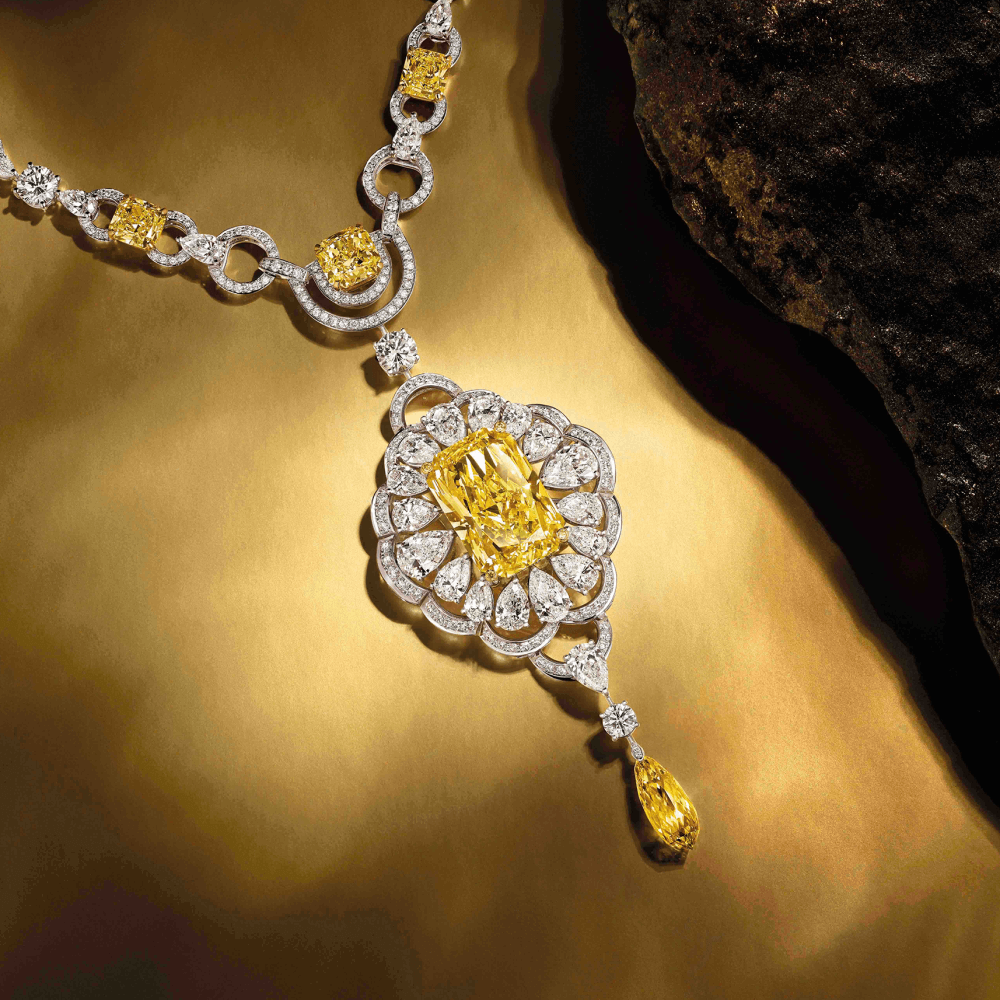 A Graff Yellow and White Diamond Necklace next to a stone