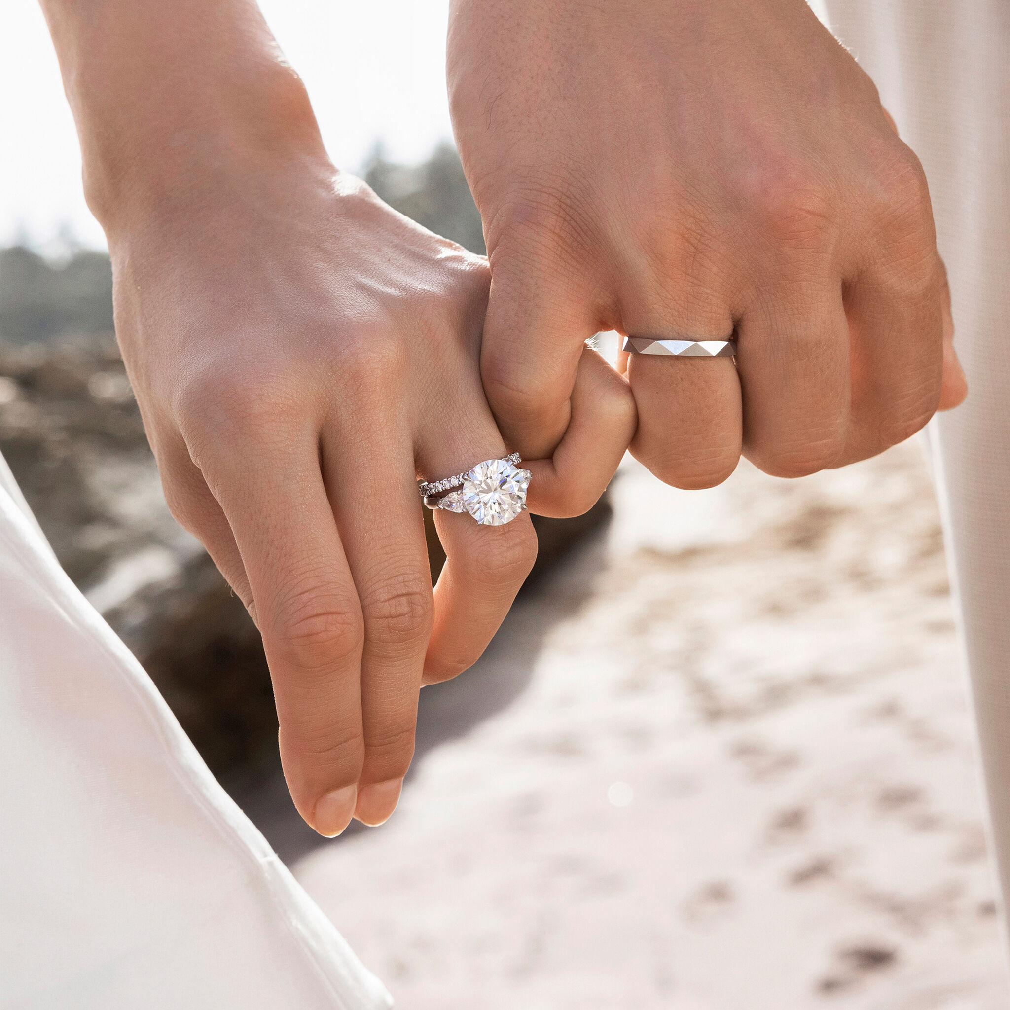 Couple wearing bridal jewellery from Graff, including a promise round diamond engagement ring and Laurence Graff Signature band.