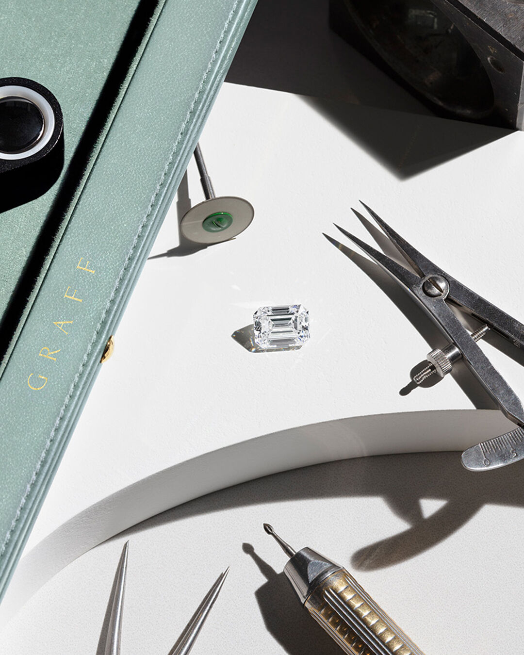 Image shows loose Graff Emerald Cut diamond and Graff workshop tools