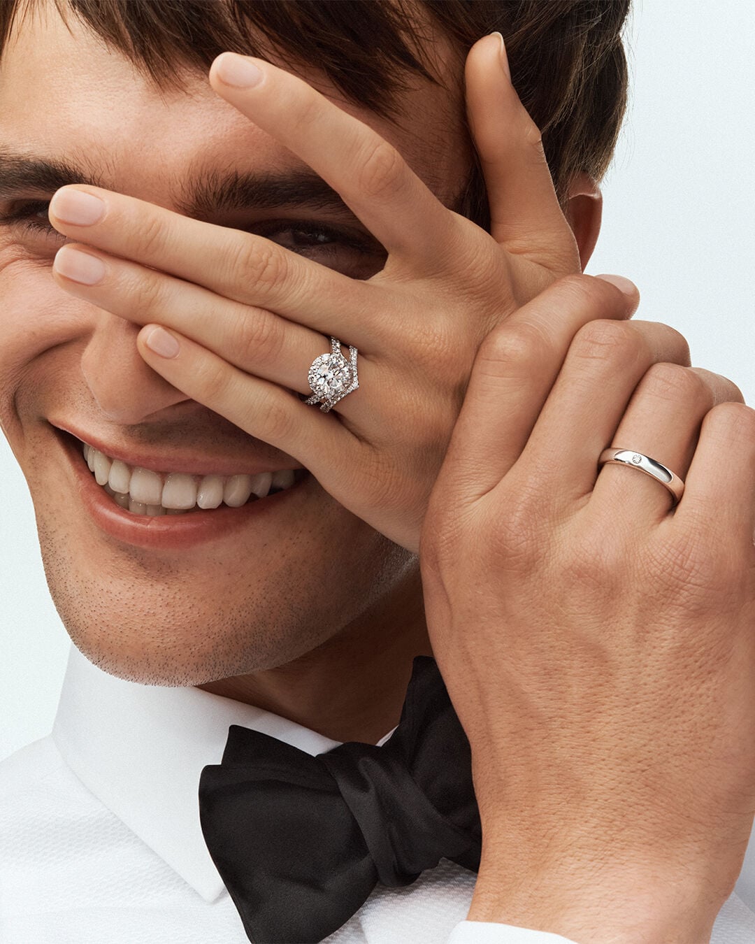 Image shows male model wearing Graff wedding band and female model hand wearing Graff Icon Round engagement ring and wedding band