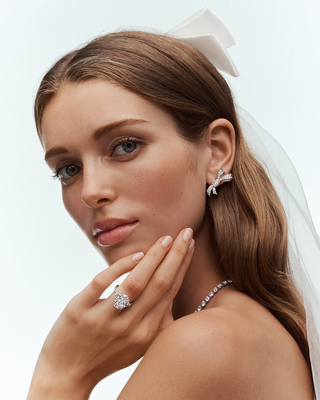 Image shows model wearing Graff Promise Oval Cut Diamond engagement ring, Tilda's Bow Earrings and round diamond necklace
