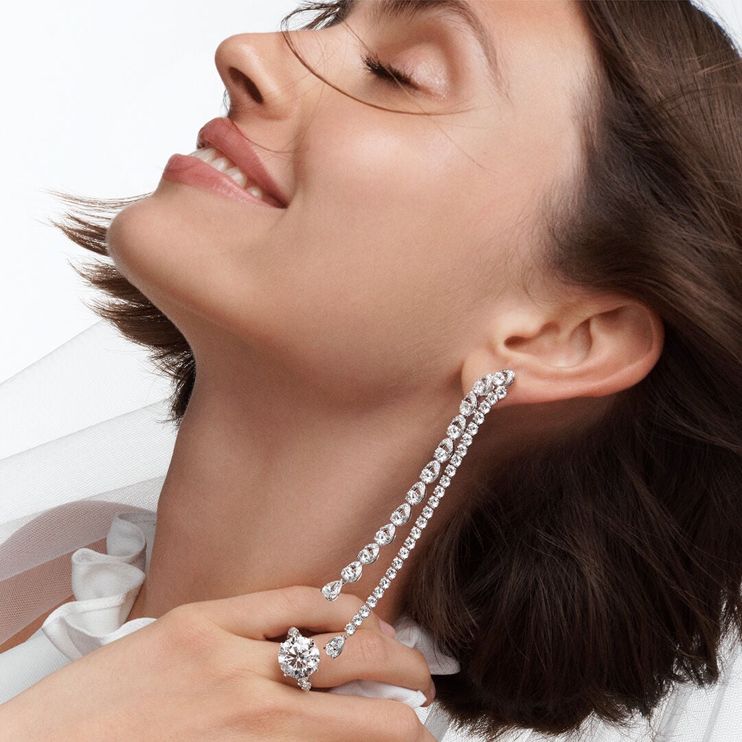 Image of model wearing Graff Promise Round Engagement ring and Classic Graff White Diamond drop earrings