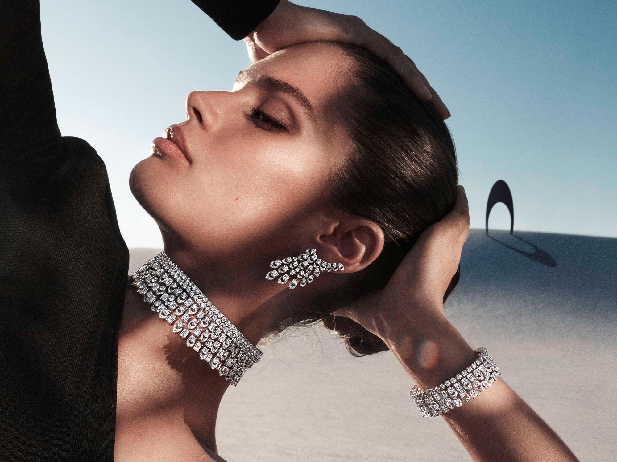 Close up of a model wearing Graff Gateway diamond earrings, necklace and bracelet from the Tribal jewellery collection, in a desert