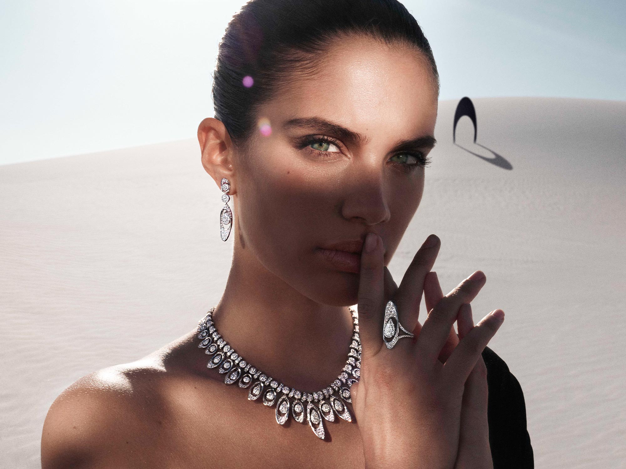 Close up of a model wearing Graff Gateway diamond earrings, necklace and ring from the Tribal jewellery collection, in a desert